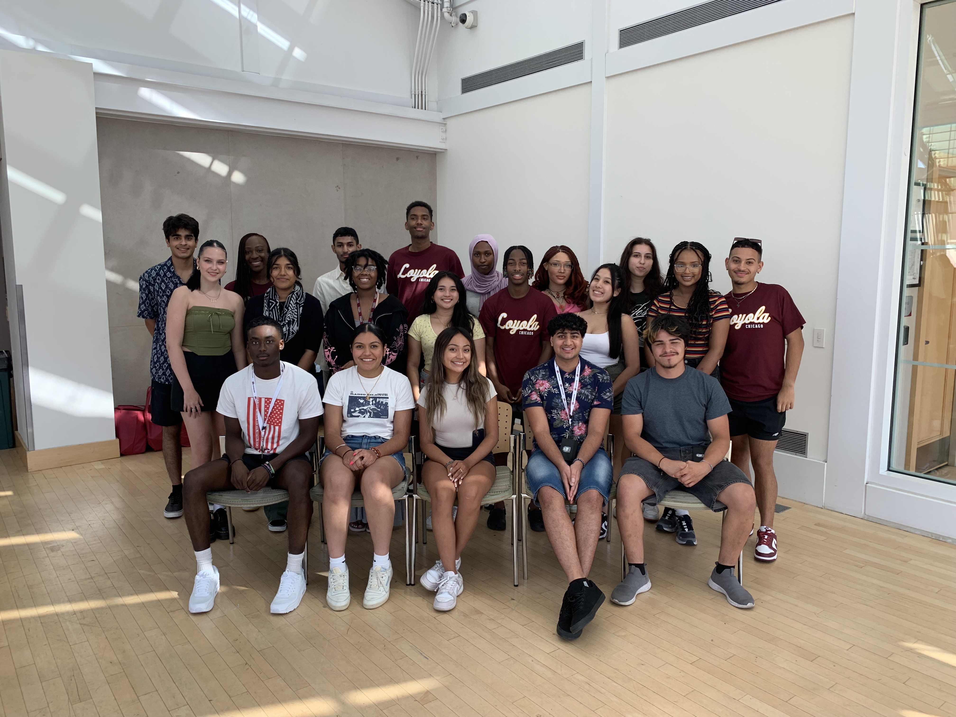 Loyola University Chicago Leadership Scholars Program Fall 2023 Cohort is in Palm Court smiling at the camera. Some Scholars are sitting in chairs in the front and the rest of the students are standing behind them.